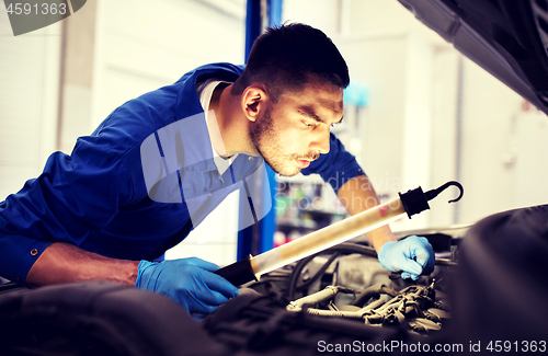 Image of mechanic man with lamp repairing car at workshop