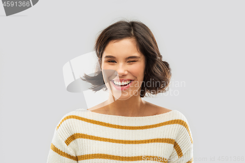 Image of happy smiling woman in striped pullover winking