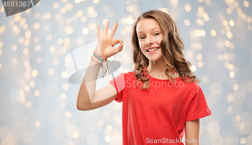 Image of smiling teenage girl in red t-shirt showing ok