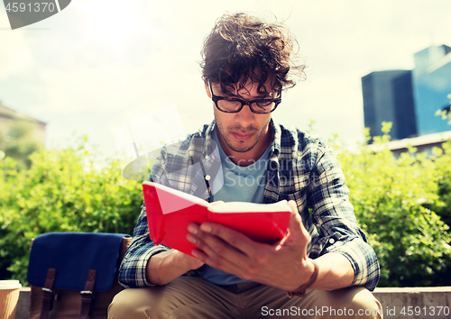 Image of man with notebook or diary writing on city street