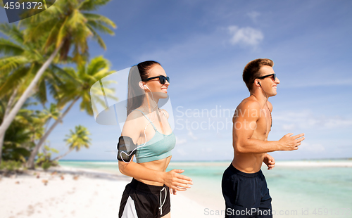 Image of couple with phones and arm bands running on beach