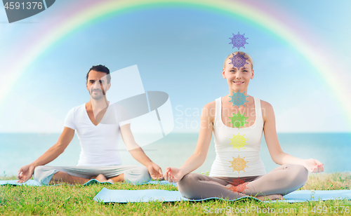 Image of couple doing yoga in lotus pose with seven chakras