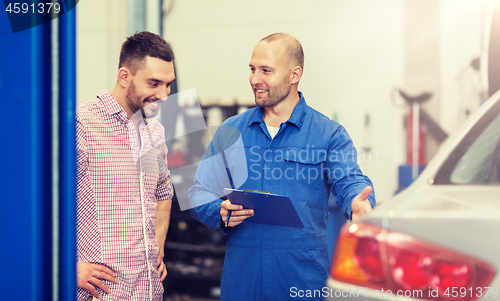 Image of auto mechanic with clipboard and man at car shop