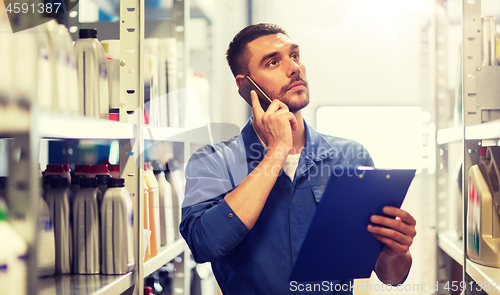 Image of auto mechanic with clipboard at car workshop