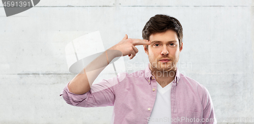 Image of bored man shooting himself by finger gun gesture