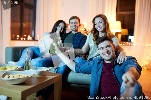 Image of happy friends taking selfie at home party