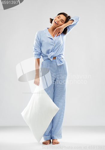 Image of happy sleepy woman in blue pajama holding pillow