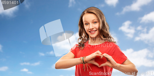 Image of smiling teenage girl in red making hand heart