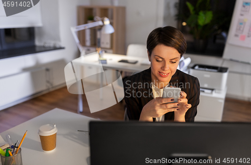 Image of businesswoman using smartphone at night office