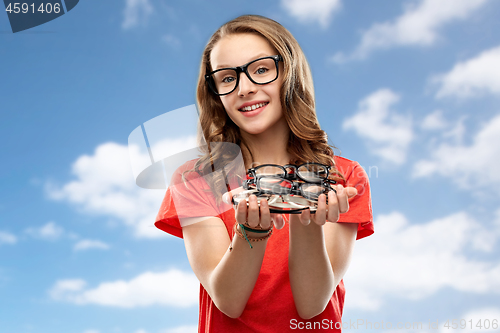 Image of teenage student girl holding glasses over sky