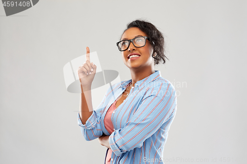 Image of african student woman in glasses points finger up