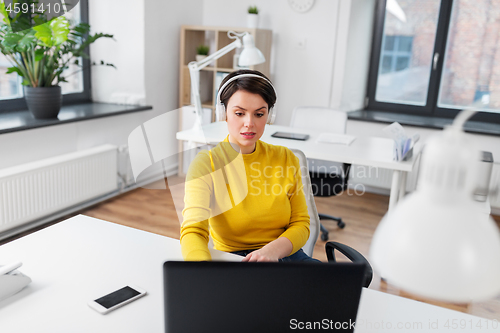 Image of businesswoman with headphones and laptop at office