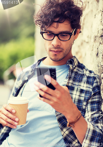 Image of man with smartphone drinking coffee on city street