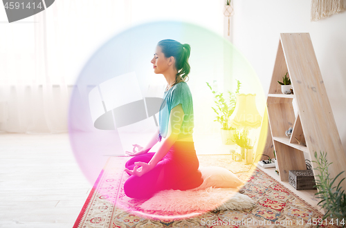 Image of woman meditating in lotus pose at yoga studio