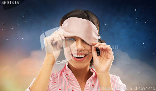 Image of happy young woman peeking from under sleeping mask