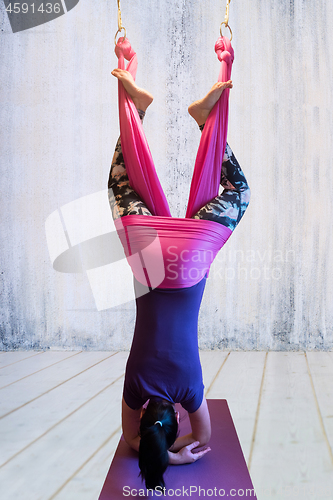 Image of Young woman making antigravity yoga exercises