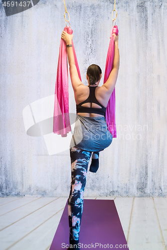 Image of Young woman making antigravity yoga exercises