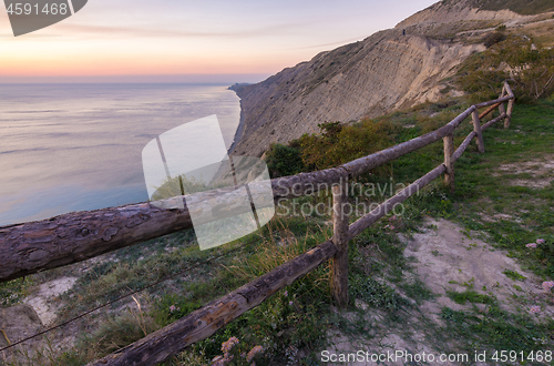 Image of A fence of tree trunks on the edge of a cliff on a rocky sea coast