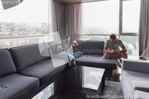 Image of two young men using a mobile phones  at home