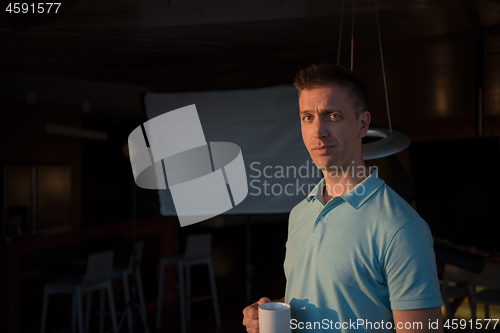 Image of young man enjoying evening coffee by the window