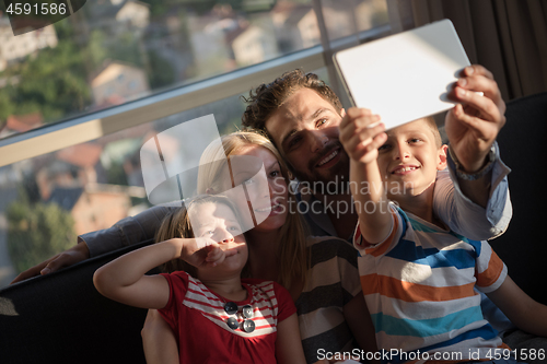 Image of happy young couple spending time with kids at home