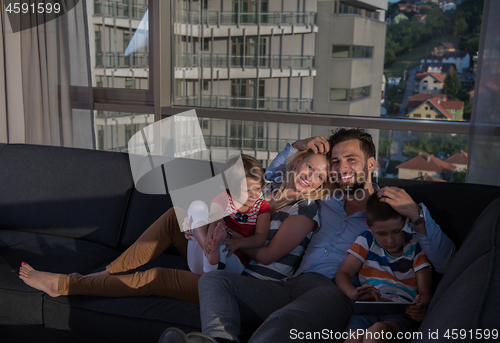 Image of happy young couple spending time with kids at home