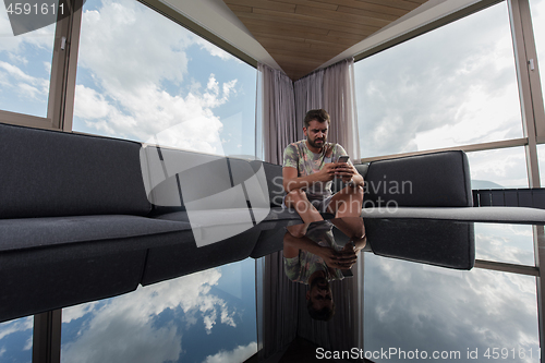 Image of young casual man using a mobile phone at home