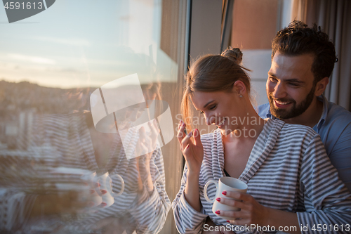 Image of young couple enjoying evening coffee by the window