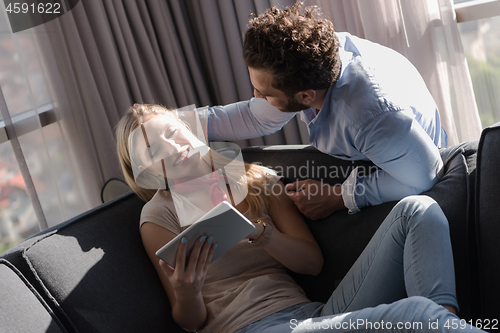 Image of couple relaxing at  home using tablet computer