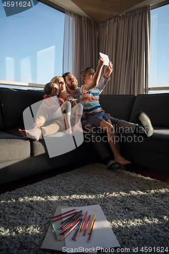 Image of happy young couple spending time with kids at home