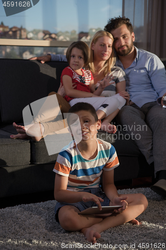 Image of happy young couple spending time with kids at home