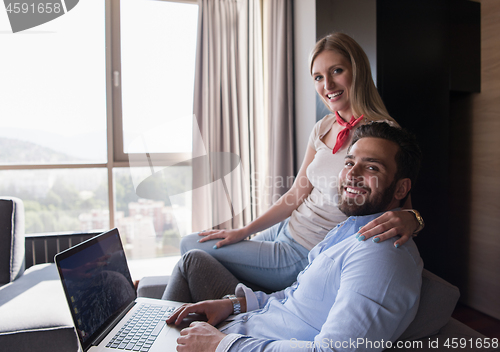 Image of couple relaxing at  home using laptop computers