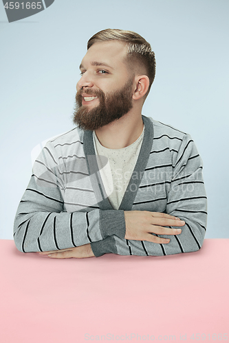 Image of The happy smiling businessman sitting at a table on a blue background