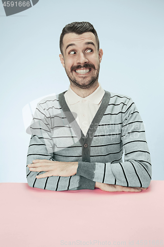 Image of The happy smiling businessman sitting at a table on a blue background