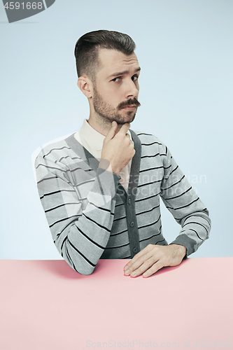 Image of Serious business man sitting at a table on a blue background