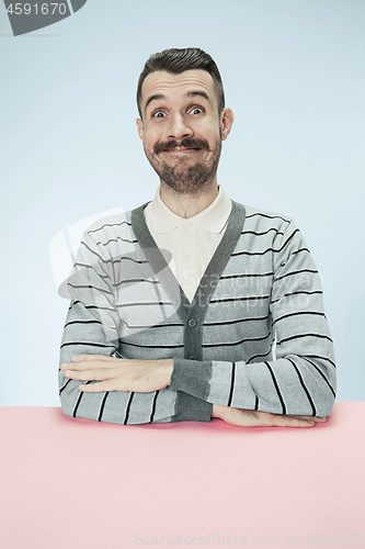 Image of The happy smiling businessman sitting at a table on a blue background