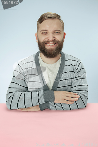 Image of The happy smiling businessman sitting at a table on a blue background