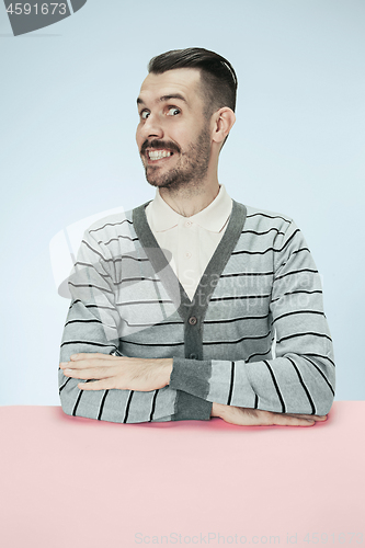 Image of The happy smiling businessman sitting at a table on a blue background