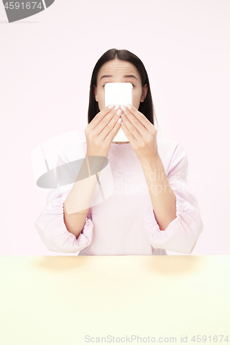 Image of The business woman sitting with mobile phone against pink background.