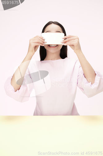 Image of The happy business woman sitting with mobile phone against pink background.