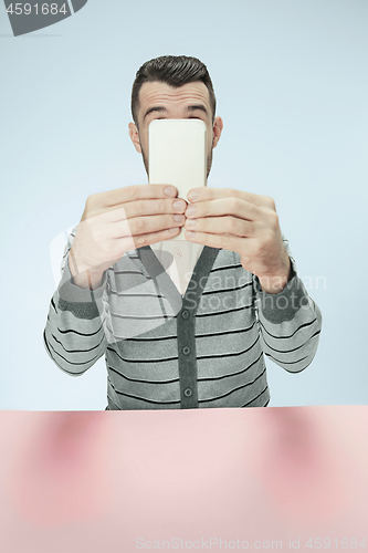 Image of Surprised business man talking on phone sitting at the table