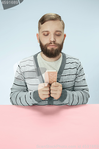 Image of Serious business man with mobile phone sitting at the table