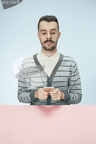 Image of Serious business man with mobile phone sitting at the table