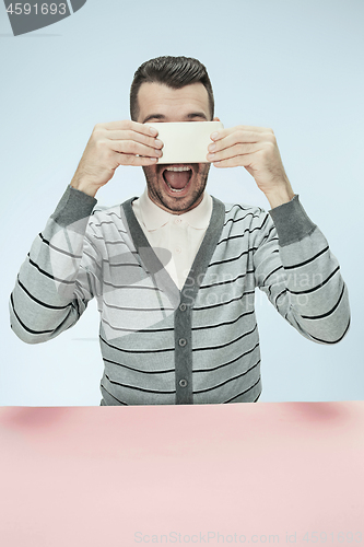 Image of Surprised business man talking on phone sitting at the table