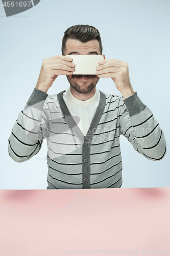 Image of Surprised business man talking on phone sitting at the table