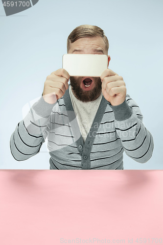 Image of Surprised business man talking on phone sitting at the table