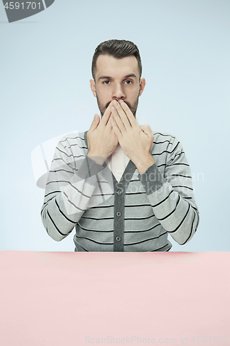 Image of Young man covering mouth by hands