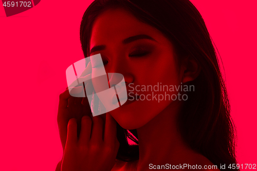 Image of High Fashion model woman in colorful bright lights posing in studio