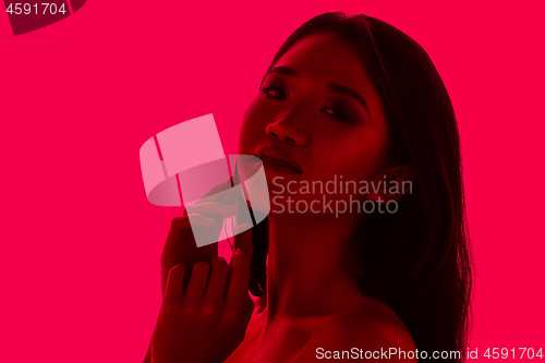 Image of High Fashion model woman in colorful bright lights posing in studio