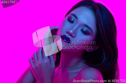 Image of High Fashion model woman in colorful bright lights posing in studio